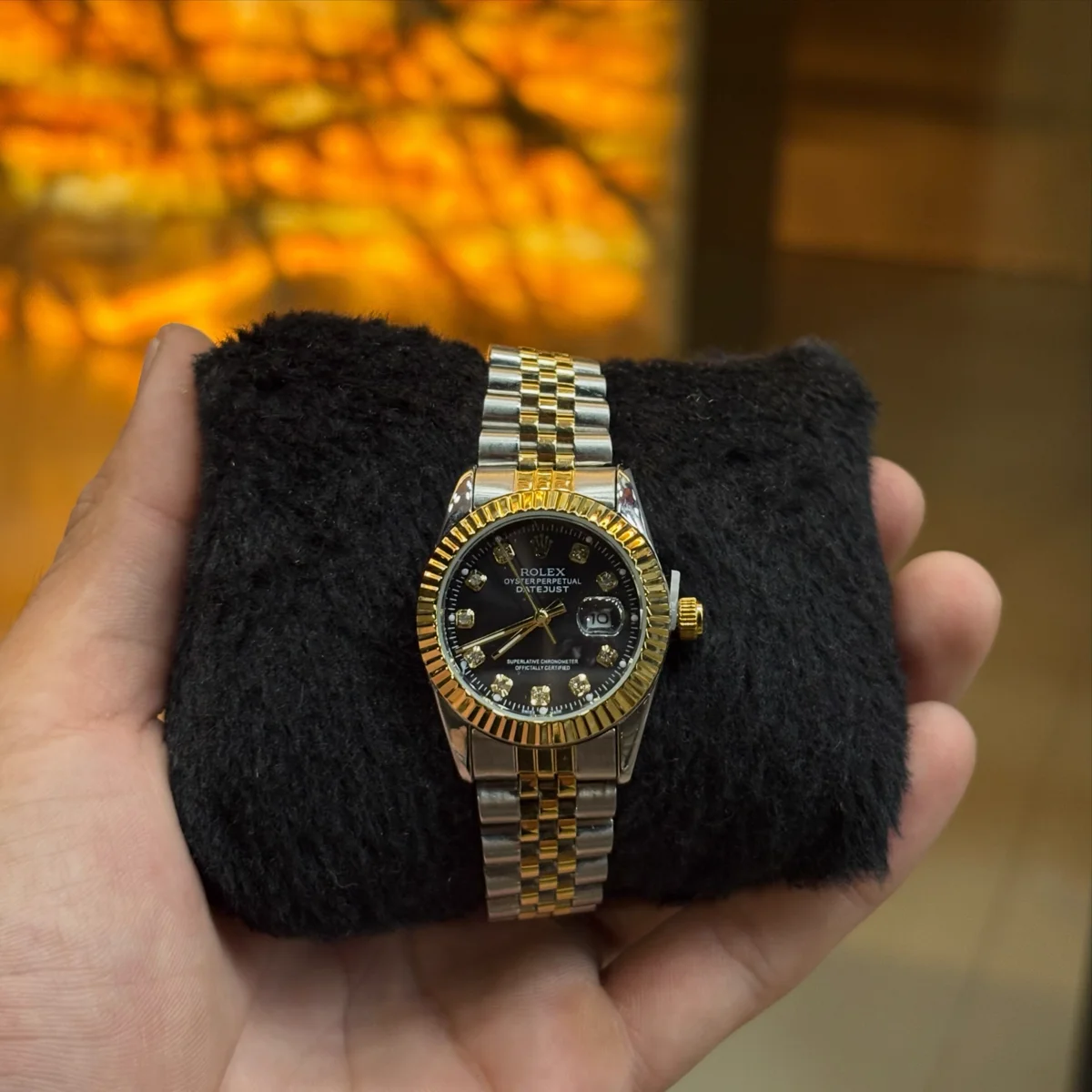 Relógio Datejust bicolor dourado e aço com mostrador preto cravejado de diamantes em almofada de veludo